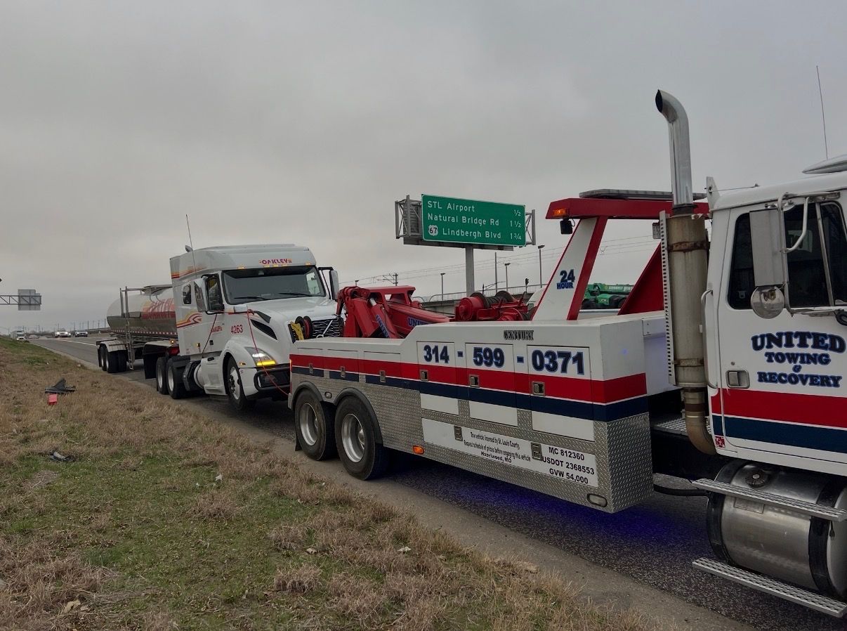 Heavy duty wrecker towing a semi on the highway near STL Airport